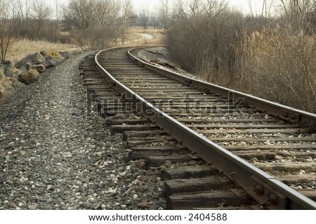 Railroad tracks curving in one direction, bike path in another