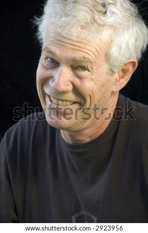 White-haired man with wicked grin, dark background