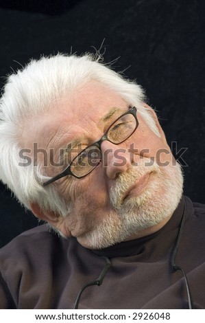 Distinguished mature man with white beard and mustache, eyeglasses, head tilted, looking thoughtfully upward, like a film director