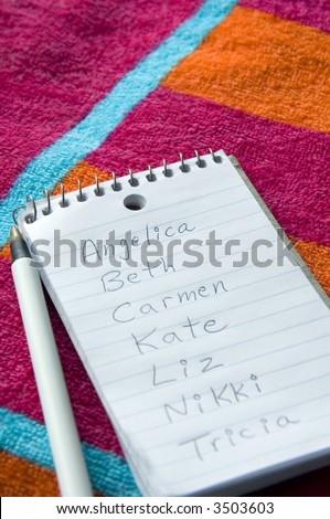 List of female names on pocket notebook on beach towel