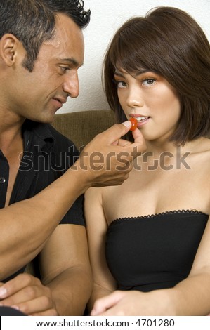 Pretty young Asian-American woman is about to accept cherry tomato from older Hispanic man
