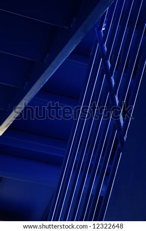 Handrails and undersides of stairs in stairwell lit by daylight from blue windows of a city parking garage
