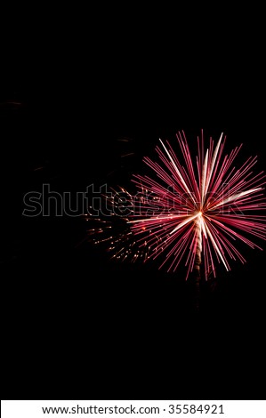 Fireworks burst with red and white streaks by \