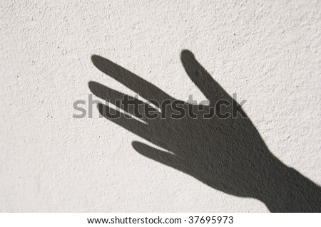 Shadow of human hand on whitewashed wall