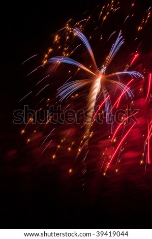 Red, white and blue burst of fireworks amid falling embers and red smoke