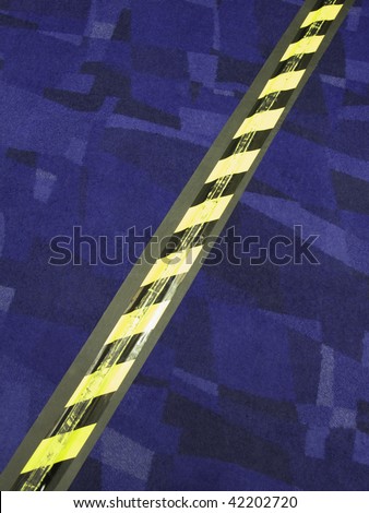 Striped safety tape over electrical cord across carpet in convention center