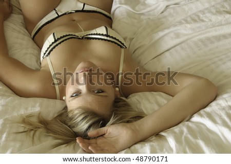 Pretty young blond in bikini underwear makes eye contact in bed