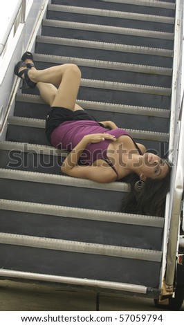 Pretty young Caucasian woman lying upside down on mobile stairs at airport