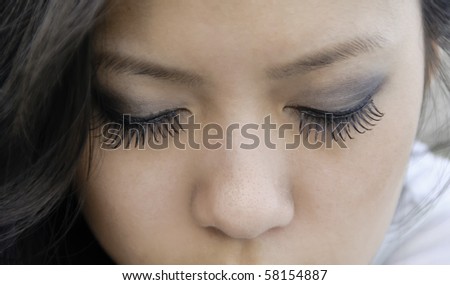 Closed eyes of young Asian-American woman with long eyelashes