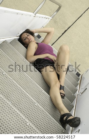 Sultry young Caucasian woman lying upside down on mobile stairs at airport