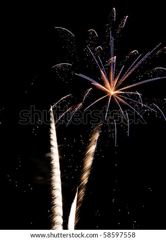 Glittery burst of blue and reddish fireworks with feathery white rocket trails