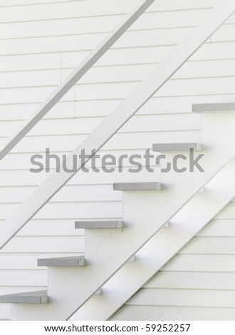 Wooden staircase on side of old-fashioned white wooden house