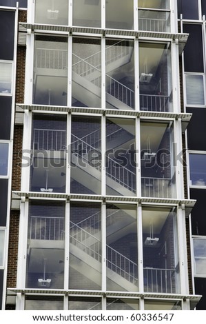 Zigzag stairway behind reflective windows of tall building