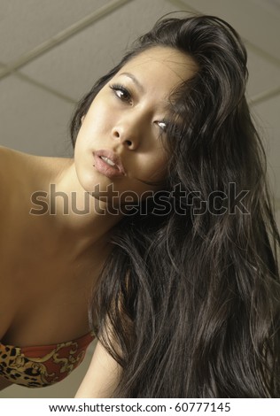 Office fantasy: beautiful young Asian-American woman in bikini top with luxuriant hair falling over her bare shoulder