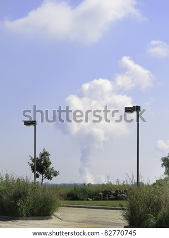 Two light posts in foreground parking lot frame a plume of steam rising from distant Dresden Nuclear Power Plant in Grundy County, Illinois