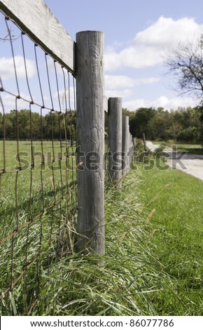 Farm fence by dirt road in American Midwest (shallow depth of field; focus on post in foreground)