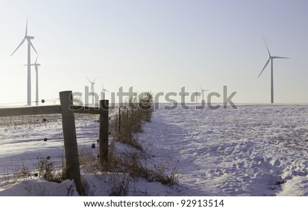 Agricultural landscape altered by technology for commercial production of electric power in northern Illinois: Recently build wind turbines tower above snowy farmland in winter