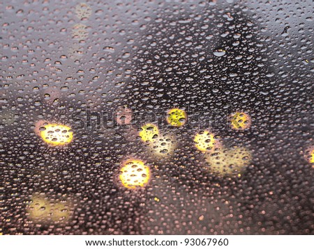 Abstract of rain at rush hour: Raindrops all over windshield (selective focus)