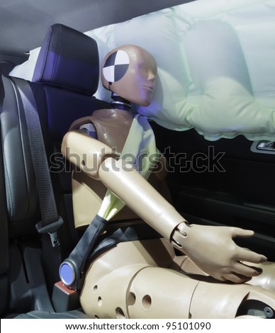 Automotive crash test dummy strapped into car seat, head against air bag