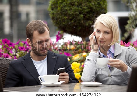 busy couple on a break in street cafe texting and calling
