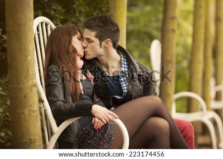 beutiful young couple kissing on bench against autumn foliage