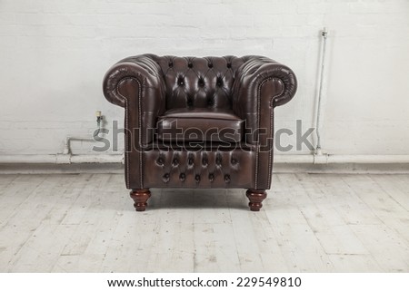 brown vintage chesterfield armchair against white painted brick wall
