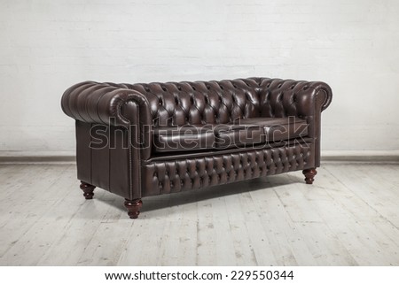 classic brown leather sofa against painted white brick wall