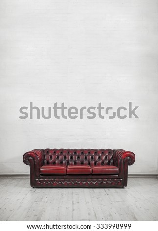 oxblood red vintage sofa against painted brick wall (place text or canvas on wall)