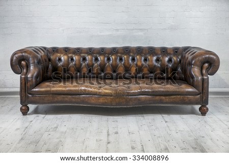 designers vintage brown chesterfield sofa against painted brick wall
