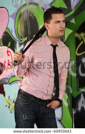 young man with baseball bat against graffiti wall