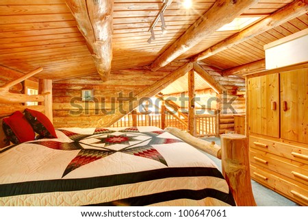 Log cabin bedroom under wood large ceiling with queen size bed.