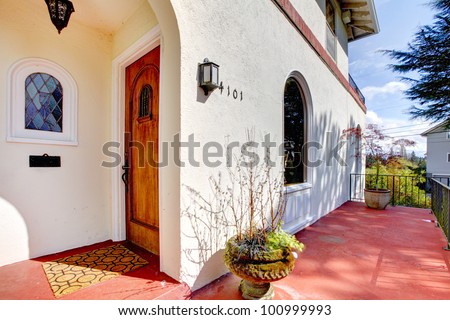 Spanish style white house with red concrete porch and front door.