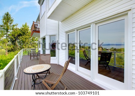 White house balcony deck with furniture and large doors.