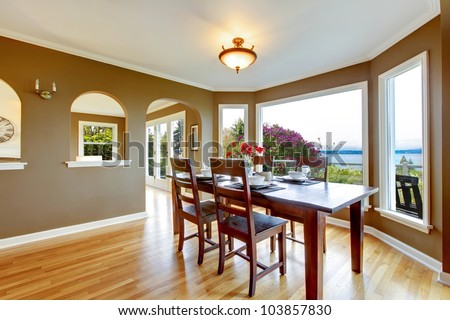 Dining room with brown walls and wood table with water view.