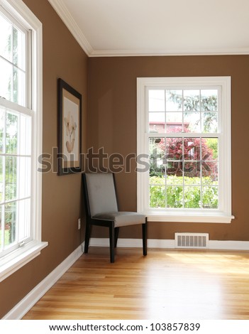 Living Room Corner With Chair And Two Windows And Hardwood Floor.