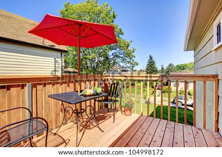 small cozy deck with red umbrella.
