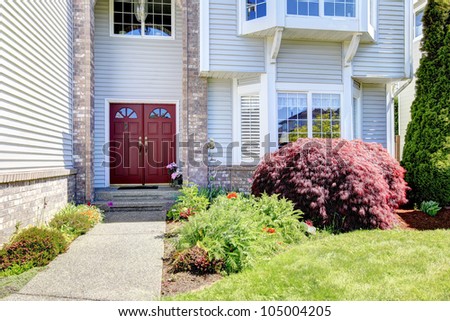 Large American  grey house with red door.