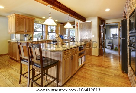 Golden warm wood kitchen with large island and back appliances.