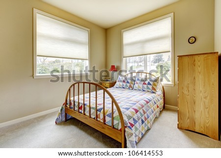 Simple bedroom with two large windows and wood bed.