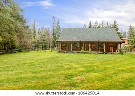 Rustic old log cabin exterior with large grass lawn.