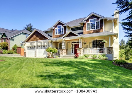 Large American beautiful house with red door and two white garage doors.