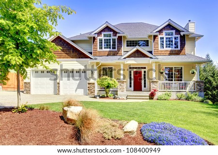 Large American beautiful house with red door and two white garage doors.
