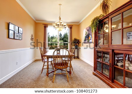 Peach color dining room with beige carpet and simple furniture.