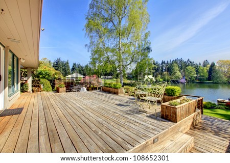 Large wood deck near house with lake and spring landscape.