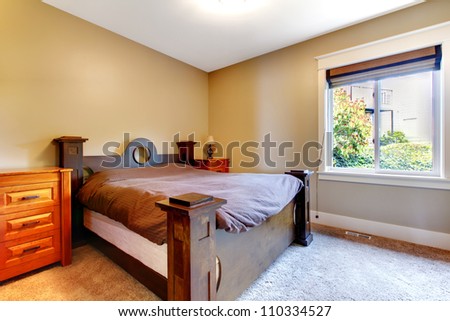 Simple classic new bedroom with nice bed and dresser with beige walls.