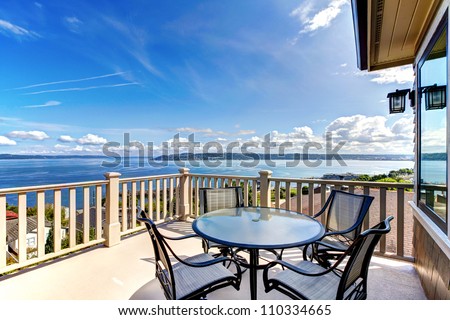 Luxury home balcony deck with water view and table with house.