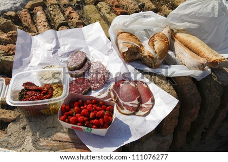 French food picnic outdoors near sea with market food on the old brick wall.