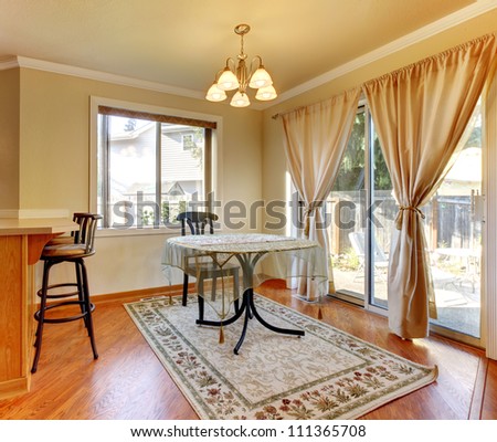 Dining room area with doors and window and simple round table and hardwood floor.