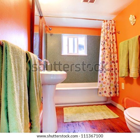 Orange and green bathroom with tub, sink  and wood floor.