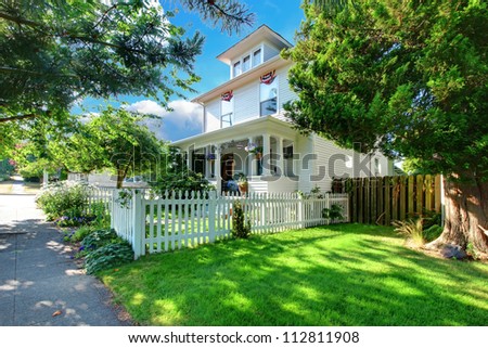 White historical American house with porch and white fence.